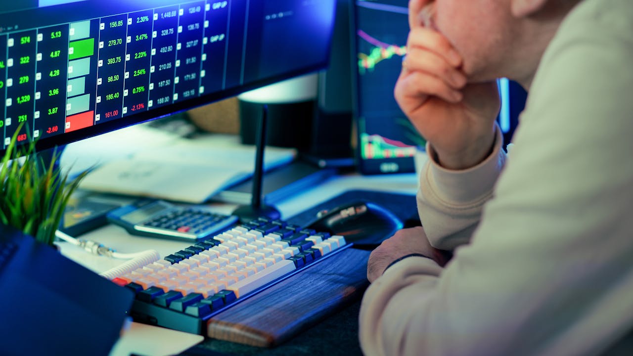 A stock trader intensely analyzing financial market data displayed on multiple screens in a modern office.